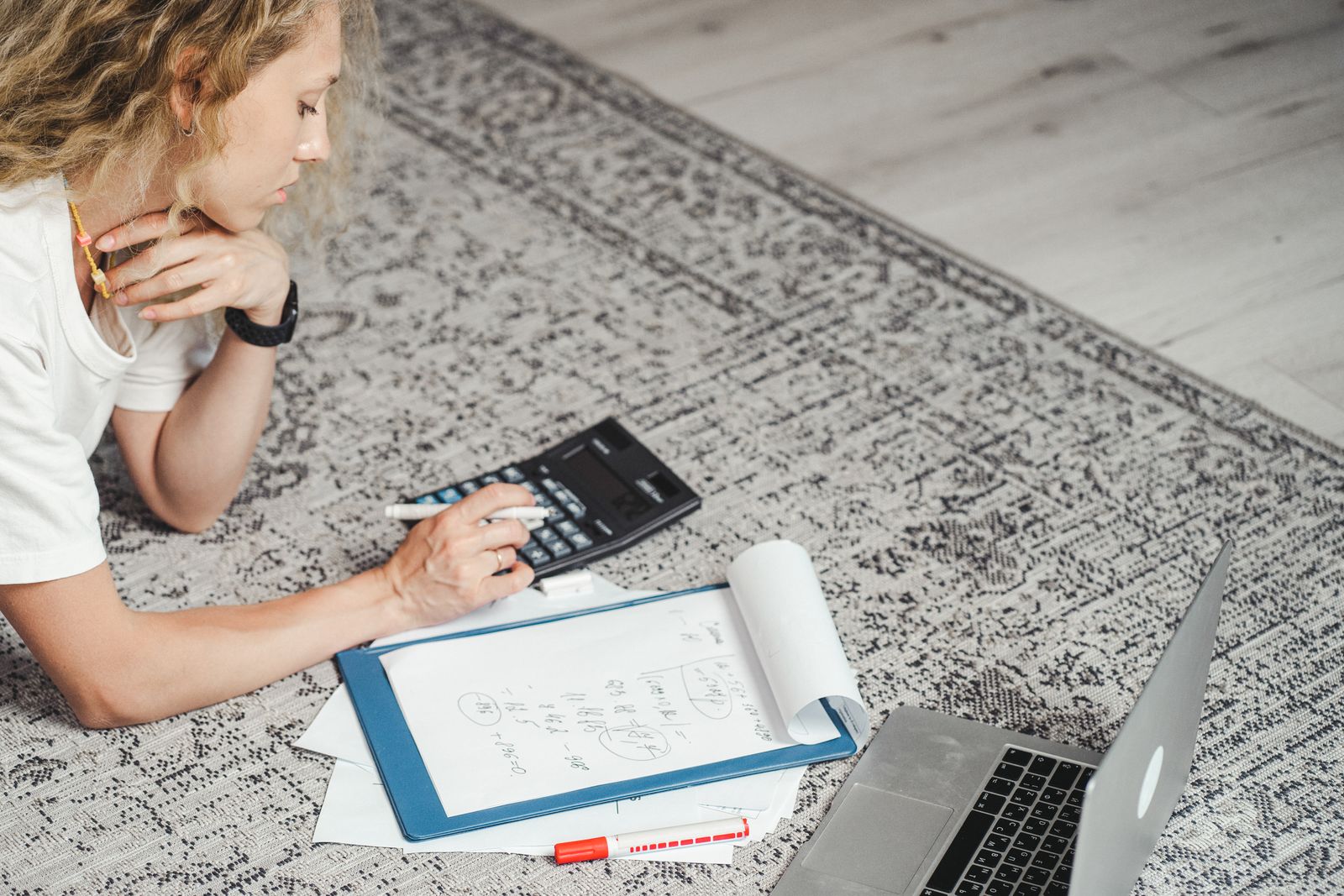 Pilates instructor working through membership pricing with a calculator, clipboard and laptop