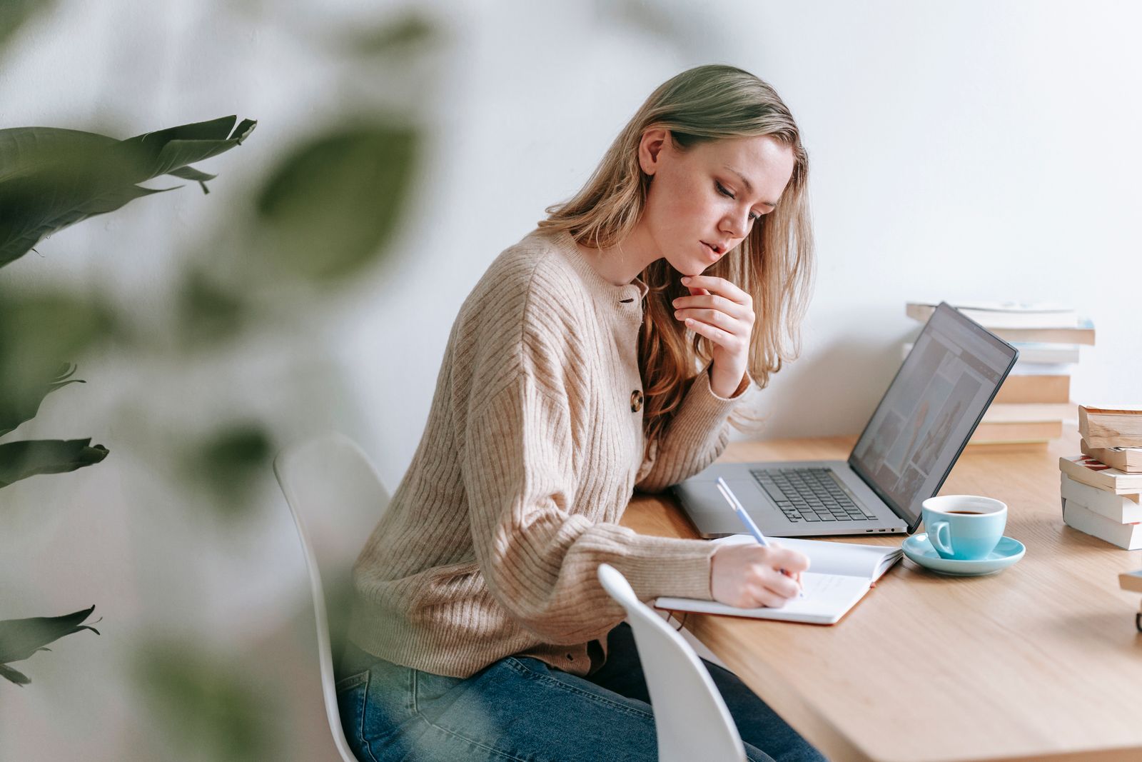 Yoga teacher working out prices in a notebook next to an open laptop